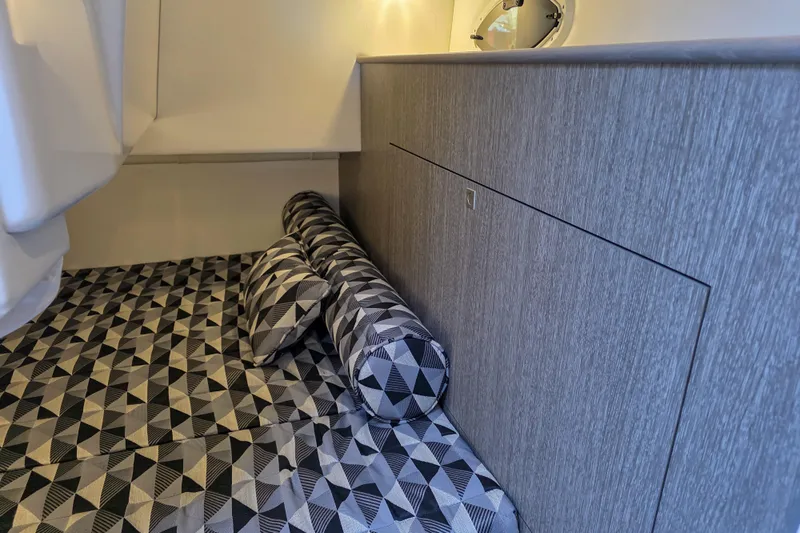  Yacht Photos Pics 2022 Monterey 295 Sport Yacht interior with geometric-patterned bedding and modern wood paneling.