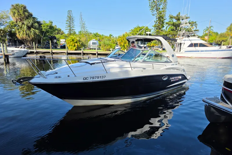  Yacht Photos Pics 2022 Monterey 295 Sport Yacht on calm water, surrounded by lush greenery.