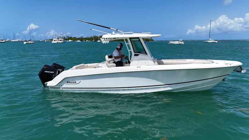  Yacht Photos Pics 2022 Boston Whaler 280 Outrage boat on clear blue water, with scenic background.