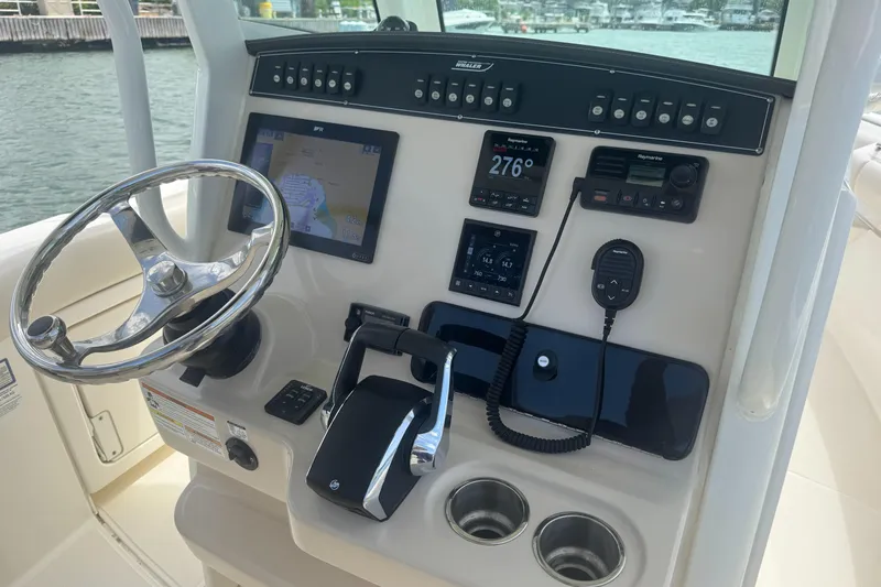  Yacht Photos Pics Control panel of 2022 Boston Whaler 280 Outrage boat with steering wheel and navigation equipment.