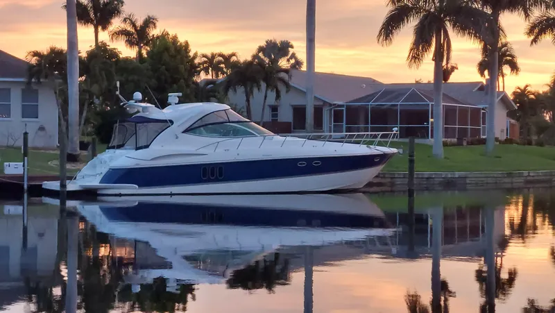 Off Line Yacht Photos Pics 2006 Cruisers Yachts 52 Express docked at sunset, reflecting on calm water.