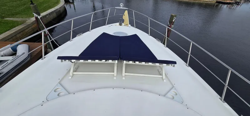 Off Line Yacht Photos Pics 2006 Cruisers Yachts 52 Express deck with blue sun loungers, docked by calm water.