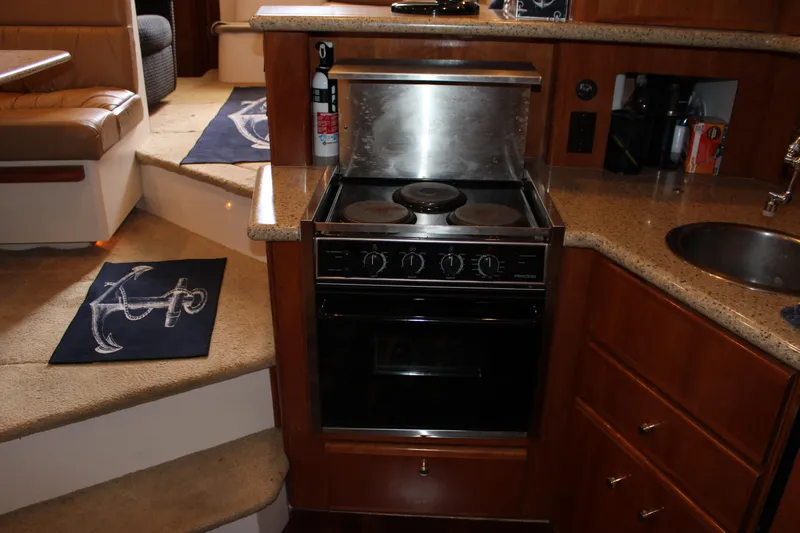  Yacht Photos Pics 2002 Carver 356 Motor Yacht kitchen with stove, sink, and wooden cabinetry.