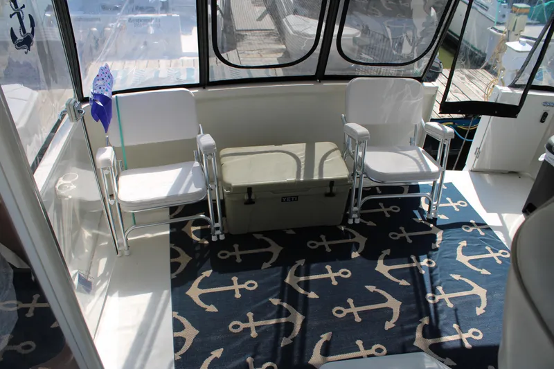  Yacht Photos Pics 2002 Carver 356 Motor Yacht interior with chairs, anchor-themed rug, and cooler.