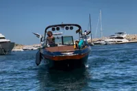 2020 MasterCraft X26 boat cruising in a marina with yachts in the background.