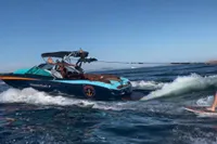 2020 MasterCraft X26 boat creating waves on a sunny day.