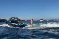2020 MasterCraft X26 boat with a person wakesurfing on a sunny day.