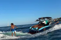 Person wakesurfing behind a 2020 MasterCraft X26 boat on a sunny day.