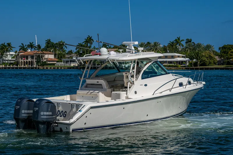  Yacht Photos Pics 2014 Pursuit 345os boat cruising on a sunny day with palm trees in the background.