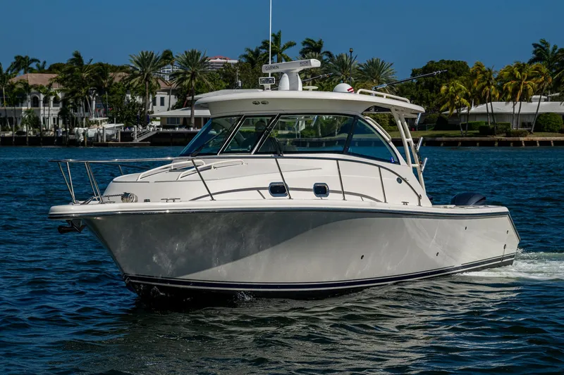  Yacht Photos Pics 2014 Pursuit 345os boat cruising on a sunny day near palm-lined shore.