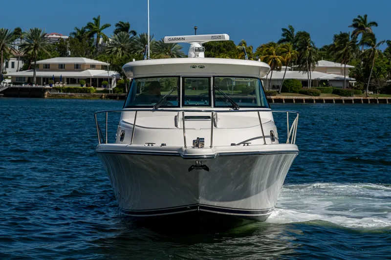  Yacht Photos Pics 2014 Pursuit 345os boat cruising on a sunny day, with waterfront homes in the background.