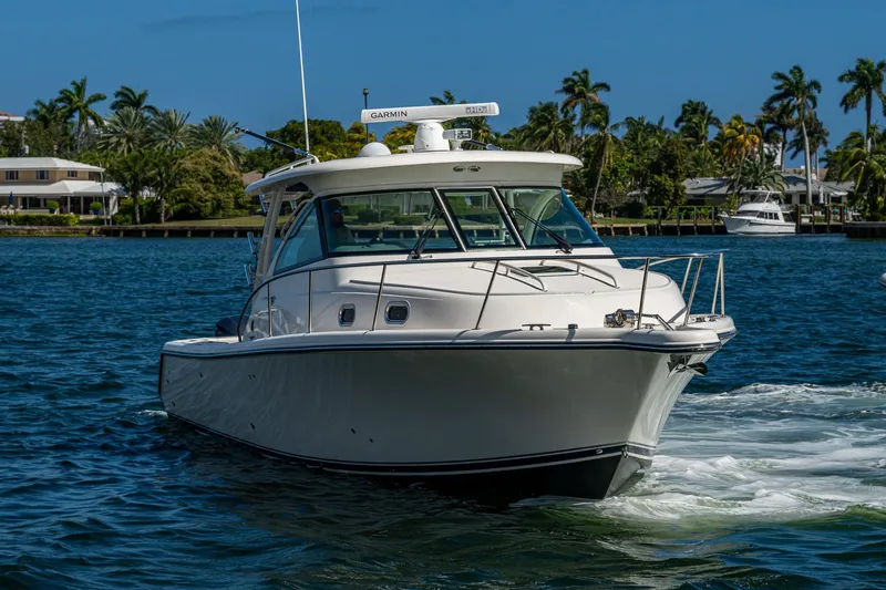  Yacht Photos Pics 2014 Pursuit 345os boat cruising on a sunny day, surrounded by palm trees and waterfront homes.