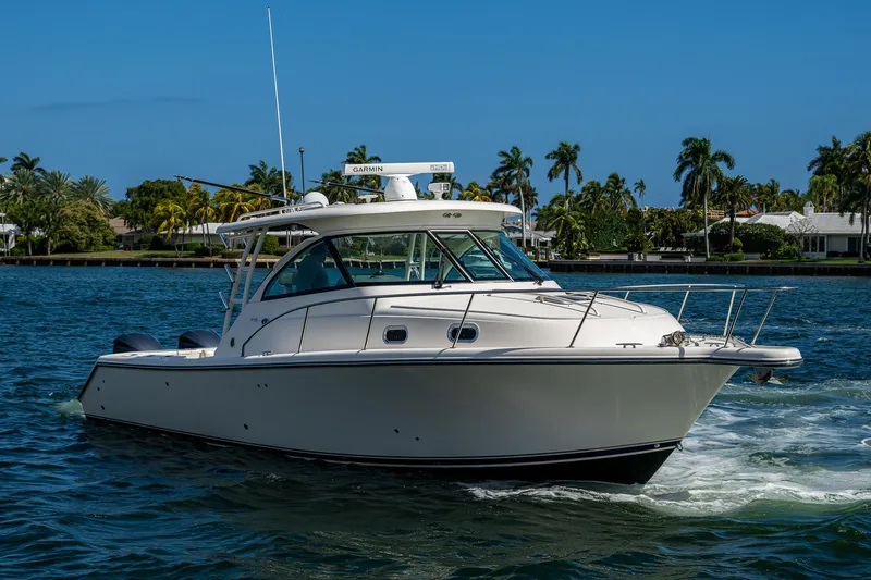  Yacht Photos Pics 2014 Pursuit 345os boat cruising on a sunny day with palm trees in the background.