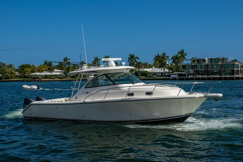  Yacht Photos Pics 2014 Pursuit 345os boat cruising on a sunny day with palm trees in the background.