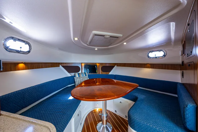  Yacht Photos Pics 2014 Pursuit 345os cabin interior with blue seating and wooden table.