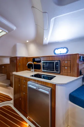  Yacht Photos Pics 2014 Pursuit 345os yacht interior with modern kitchen, wood cabinetry, and stainless steel appliances.