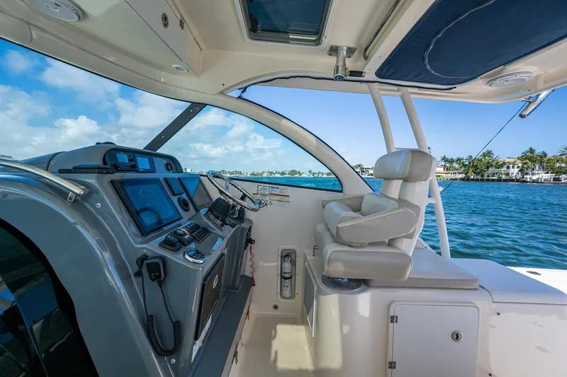  Yacht Photos Pics 2014 Pursuit 345os boat cockpit with modern controls, overlooking a scenic waterfront.