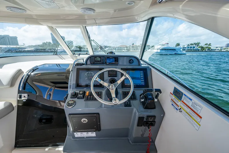  Yacht Photos Pics 2014 Pursuit 345os boat helm with steering wheel, controls, and navigation screens on a sunny day.