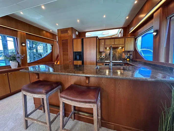 Safari Yacht Photos Pics Luxurious kitchen interior of 2001 Symbol 66 Pilothouse Yacht with wooden cabinetry and granite countertops.