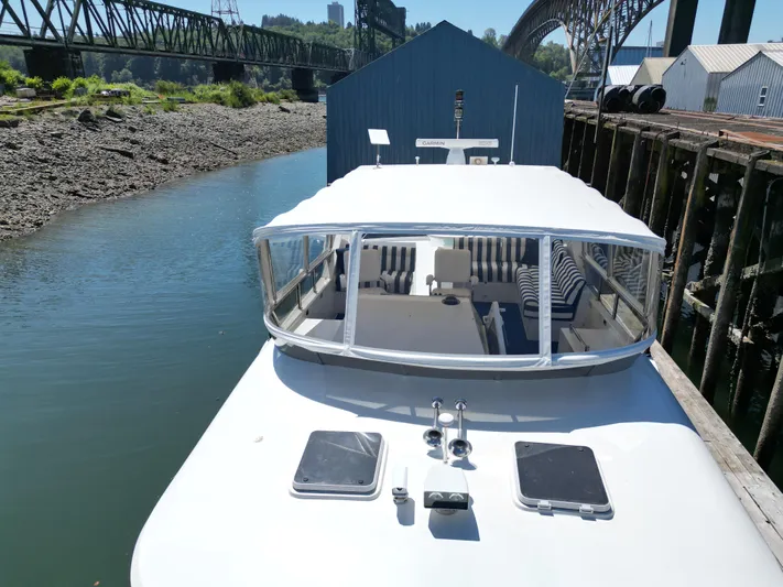 Safari Yacht Photos Pics 2001 Symbol 66 Pilothouse Yacht docked by a bridge, featuring spacious deck and seating area.