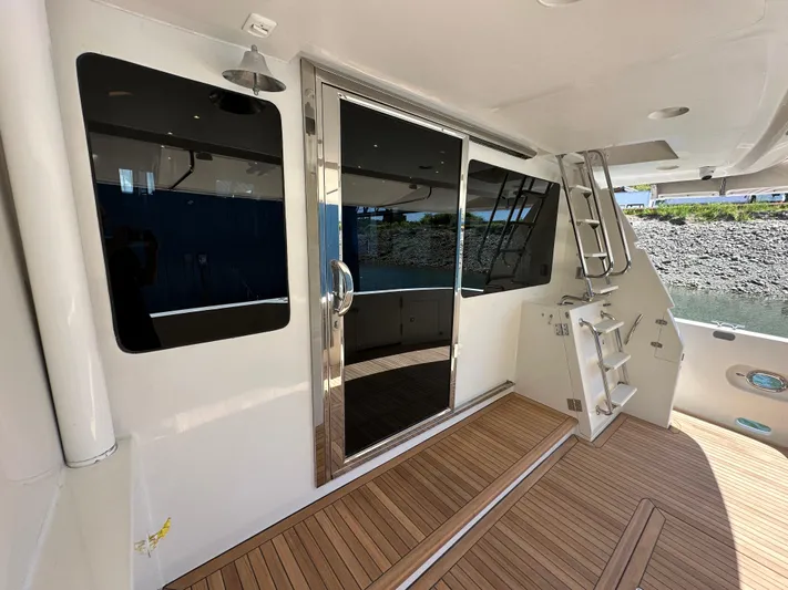 Safari Yacht Photos Pics 2001 Symbol 66 Pilothouse Yacht deck with sliding glass door and wooden flooring.