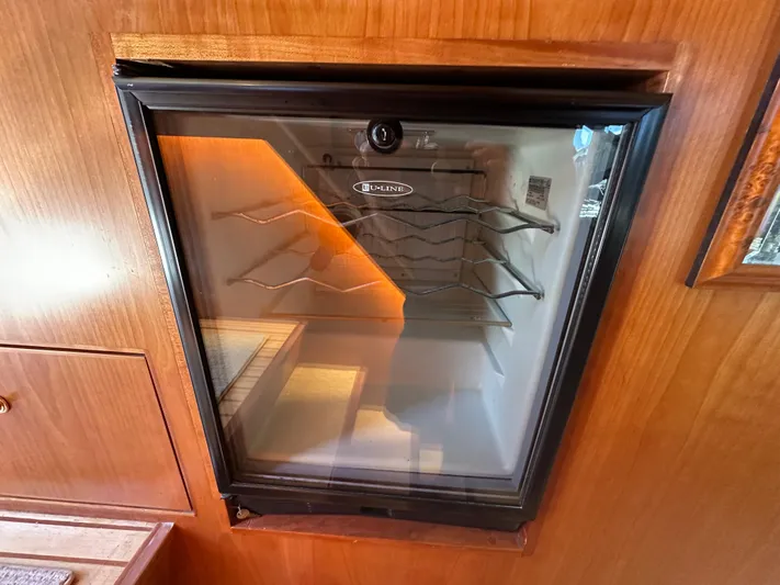 Safari Yacht Photos Pics Wine cooler in 2001 Symbol 66 Pilothouse Yacht interior, featuring wooden cabinetry.