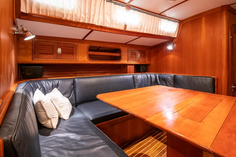 Regulus Yacht Photos Pics Interior of 1993 Hinckley Sou'wester 51 yacht with wooden table and blue seating.