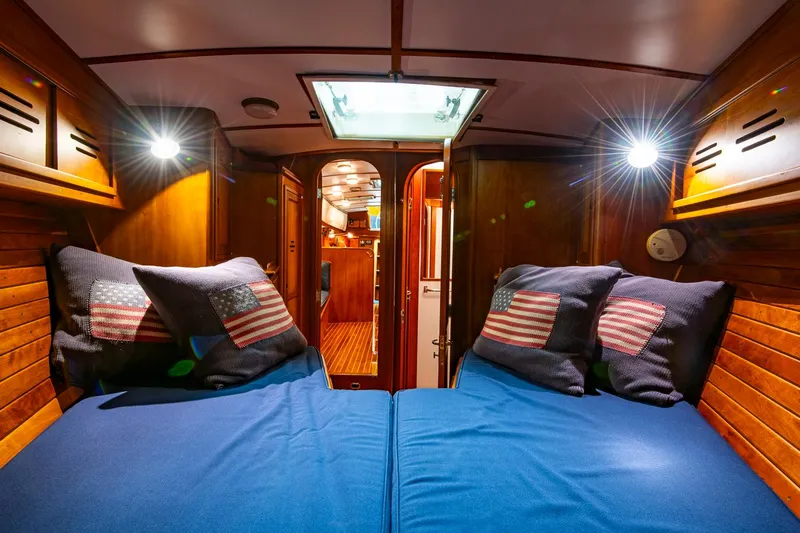Regulus Yacht Photos Pics Cozy cabin interior of 1993 Hinckley Sou'wester 51 sailboat with blue bedding and American flag pillows.