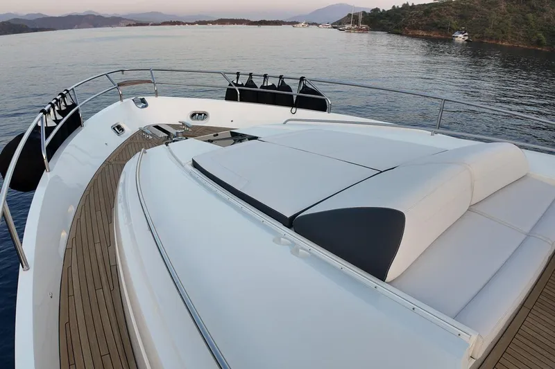 On Yacht Photos Pics Luxurious 2014 Princess 82 yacht deck with sunbed, overlooking serene waters and distant hills.