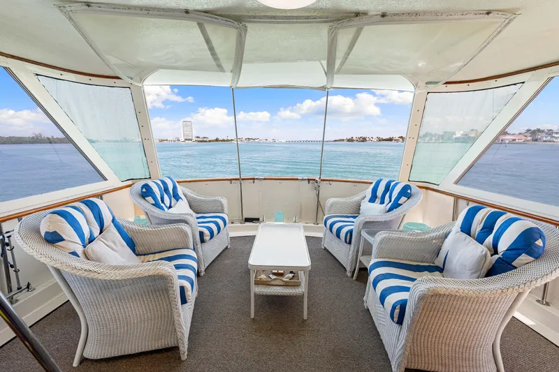 Lattitude Yacht Photos Pics 1979 Hatteras 53 Motor Yacht interior with wicker chairs, blue-striped cushions, and ocean view.
