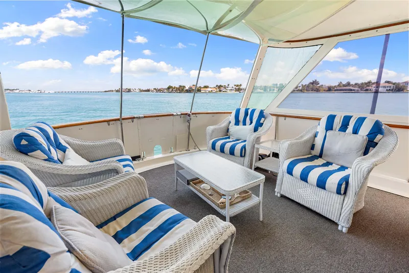 Lattitude Yacht Photos Pics 1979 Hatteras 53 Motor Yacht deck with striped seating, overlooking serene waters.