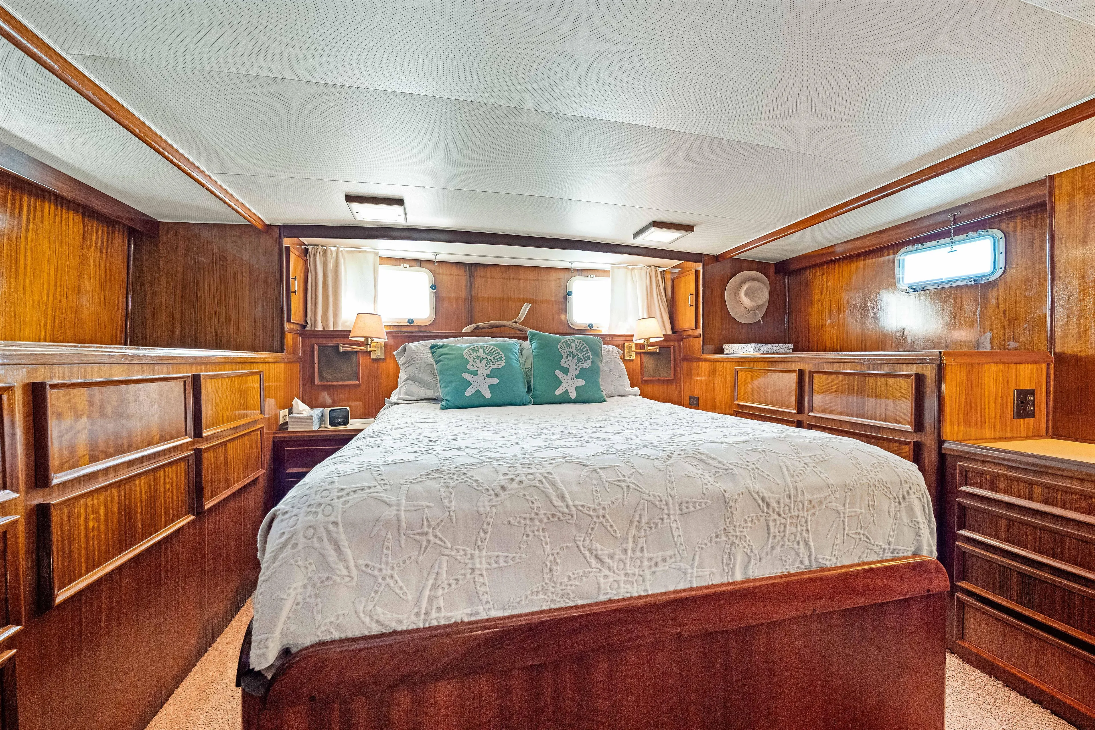 Lattitude Yacht Photos Pics Luxurious 1979 Hatteras 53 Motor Yacht bedroom with elegant wood paneling and cozy bedding.