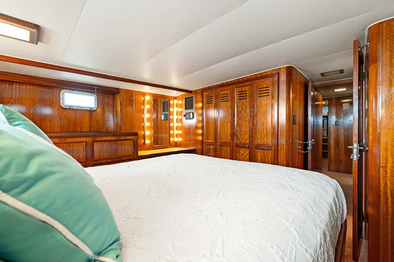 Lattitude Yacht Photos Pics Luxurious 1979 Hatteras 53 Motor Yacht cabin with wood paneling and cozy bedding.