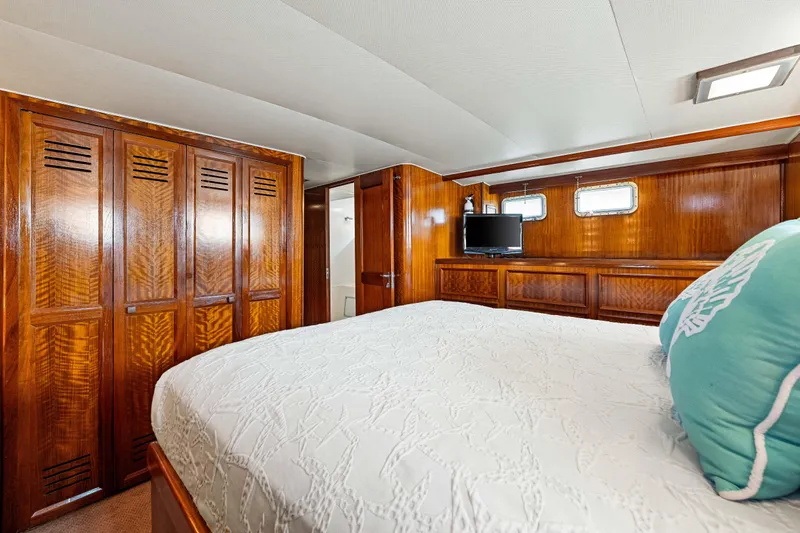 Lattitude Yacht Photos Pics Luxurious cabin interior of 1979 Hatteras 53 Motor Yacht with wood paneling and cozy bedding.