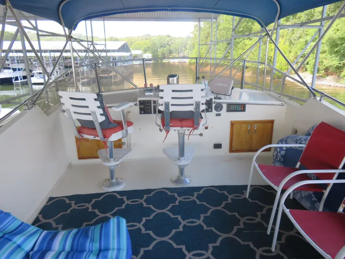 Rive' Gauche Yacht Photos Pics 1986 Hatteras 58 Motor Yacht helm with seating, blue canopy, and marina view.