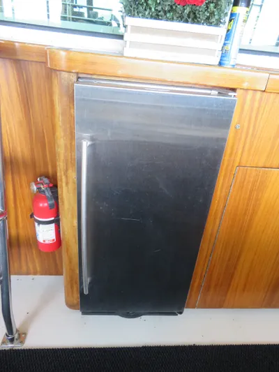 Rive' Gauche Yacht Photos Pics Stainless steel fridge on 1986 Hatteras 58 Motor Yacht with wooden cabinetry and fire extinguisher.