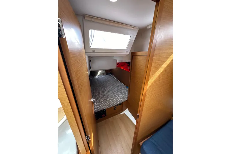  Yacht Photos Pics Cabin interior of 2019 Jeanneau Sun Odyssey 440 sailboat, featuring a cozy bed and wooden finish.