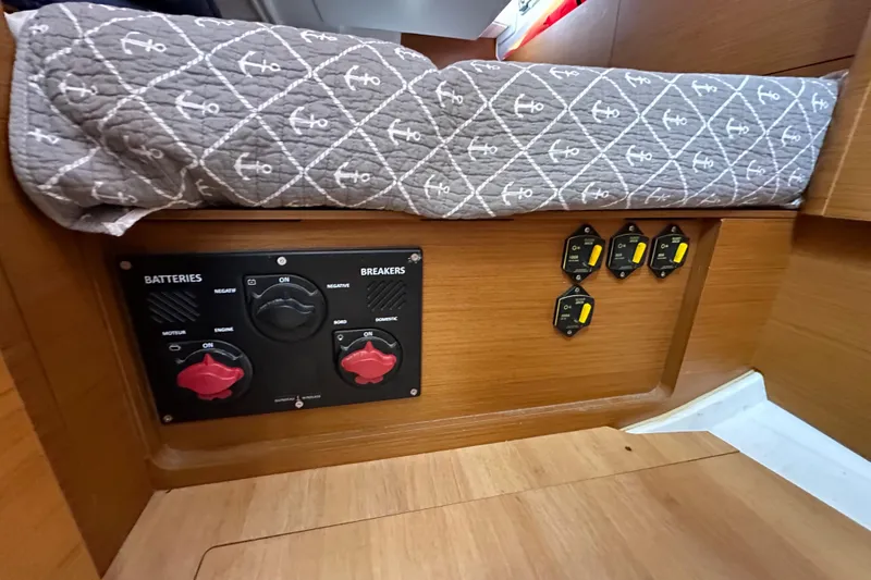  Yacht Photos Pics 2019 Jeanneau Sun Odyssey 440 interior showing battery and breaker panel under a patterned cushion.