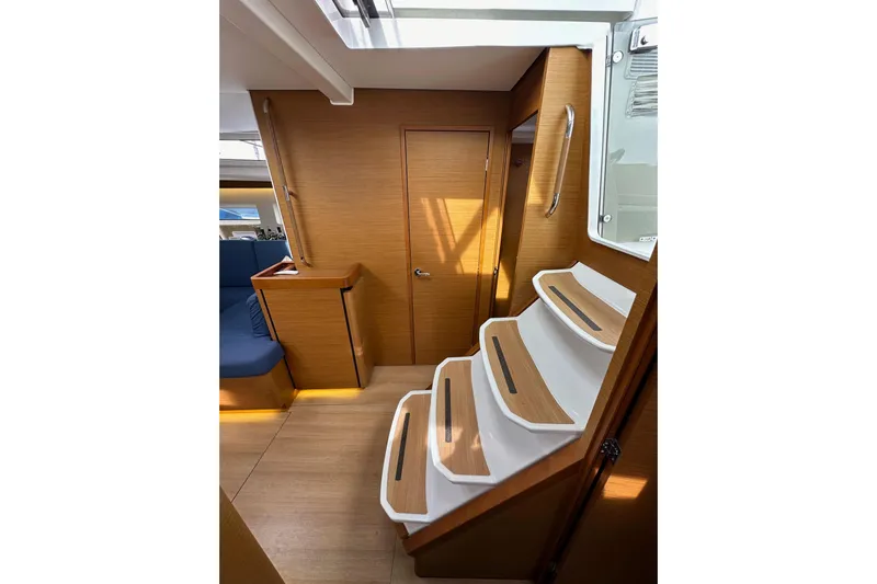  Yacht Photos Pics Interior of 2019 Jeanneau Sun Odyssey 440 yacht with wooden stairs and seating area.