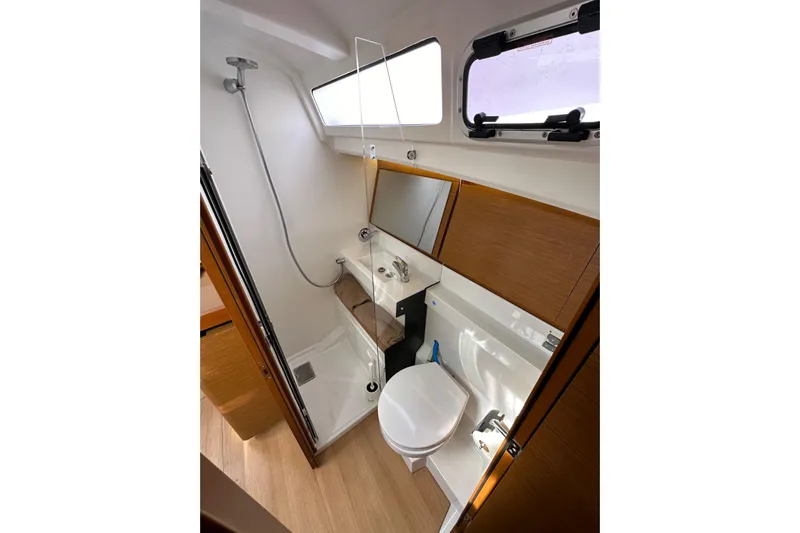  Yacht Photos Pics 2019 Jeanneau Sun Odyssey 440 bathroom with shower, toilet, and wooden cabinetry.