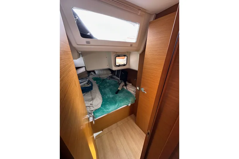  Yacht Photos Pics Cozy cabin interior of 2019 Jeanneau Sun Odyssey 440 sailboat with bedding and wooden finish.