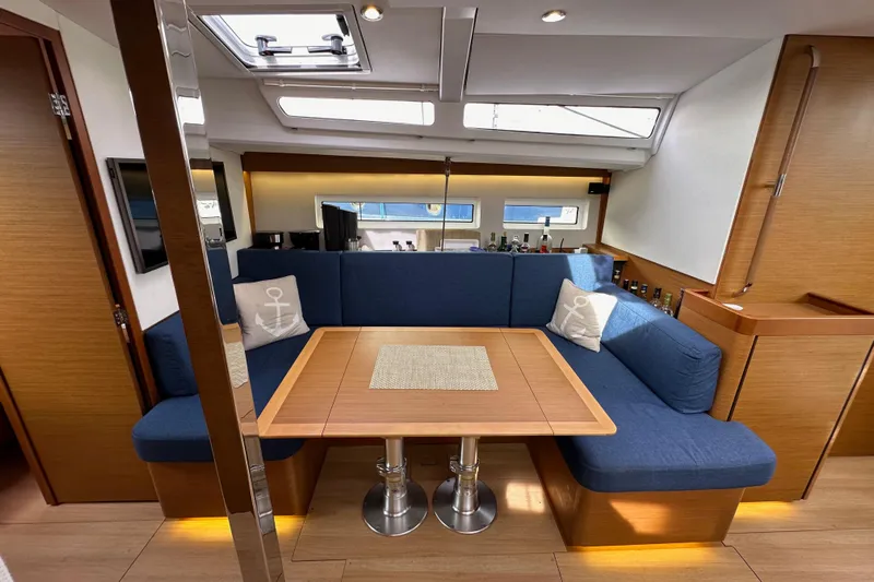  Yacht Photos Pics 2019 Jeanneau Sun Odyssey 440 interior with blue seating, wooden table, and nautical decor.