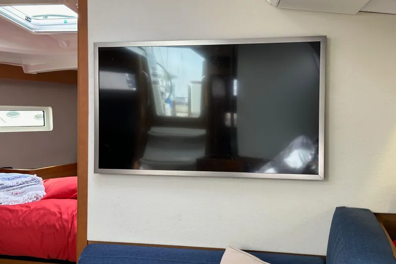  Yacht Photos Pics Interior of 2019 Jeanneau Sun Odyssey 440 with wall-mounted TV and cozy seating area.
