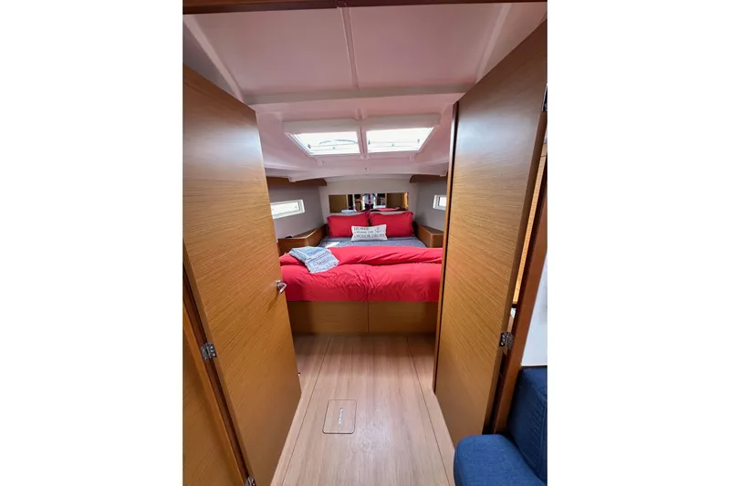  Yacht Photos Pics Cozy cabin interior of 2019 Jeanneau Sun Odyssey 440 with red bedding and wooden finish.