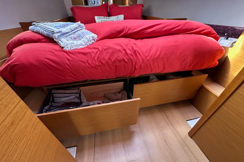  Yacht Photos Pics Cozy cabin interior of 2019 Jeanneau Sun Odyssey 440 with red bedding and storage drawers.