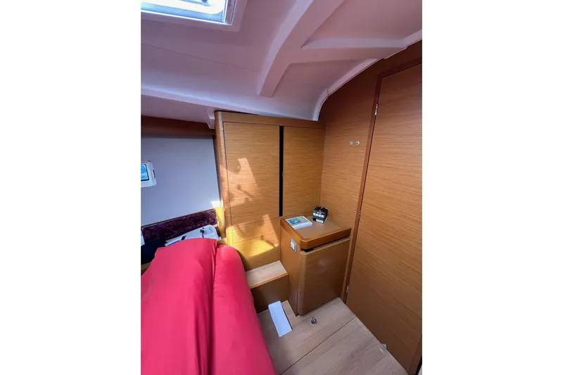  Yacht Photos Pics Interior of 2019 Jeanneau Sun Odyssey 440 yacht, featuring wooden cabinetry and red bedding.