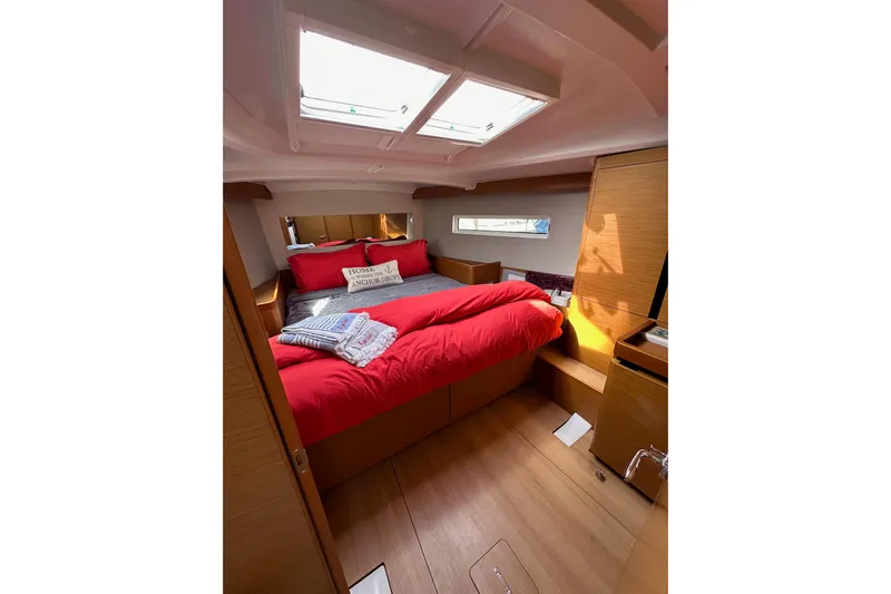  Yacht Photos Pics Cozy cabin interior of 2019 Jeanneau Sun Odyssey 440 with red bedding and skylight.