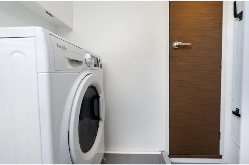  Yacht Photos Pics 2022 Prestige X70 laundry area with washing machine and wooden door.