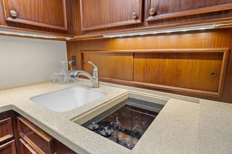 Bella Yacht Photos Pics 1978 Hatteras 45 Convertible yacht kitchen with sink and stove, wooden cabinetry.