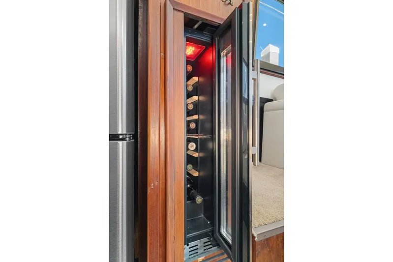 Bella Yacht Photos Pics Wine cooler inside 1978 Hatteras 45 Convertible yacht, showcasing bottles and elegant wood finish.